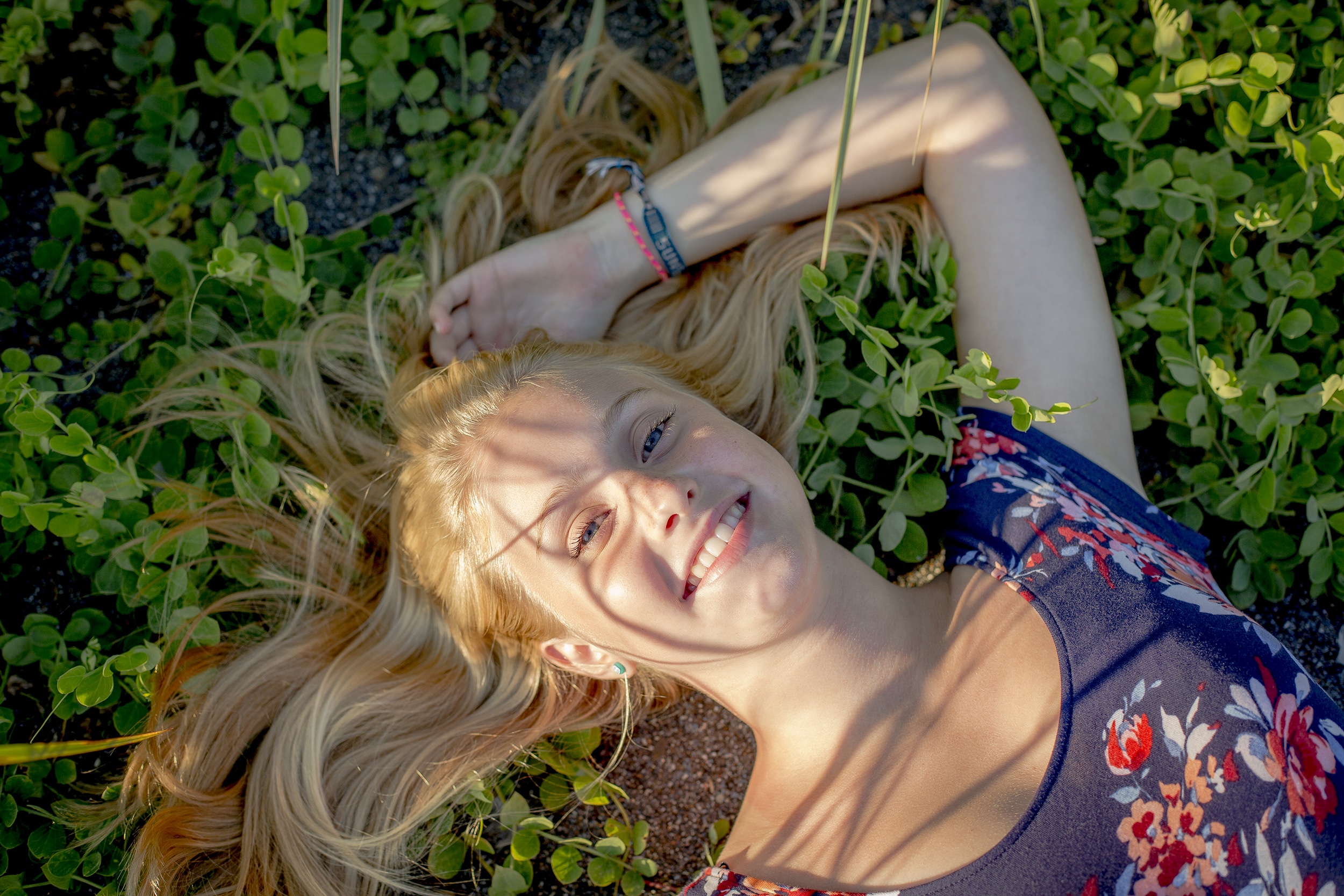 Young woman relaxing on lush plants outdoors.