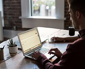 Modern workspace with a person working on a laptop, surrounded by plants and natural light.