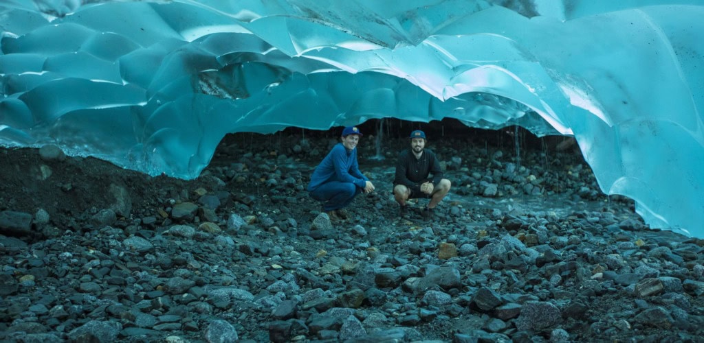 Billy Holbrook (left) and Zander Hoke (right) crouching inside a blue glacier ice cave