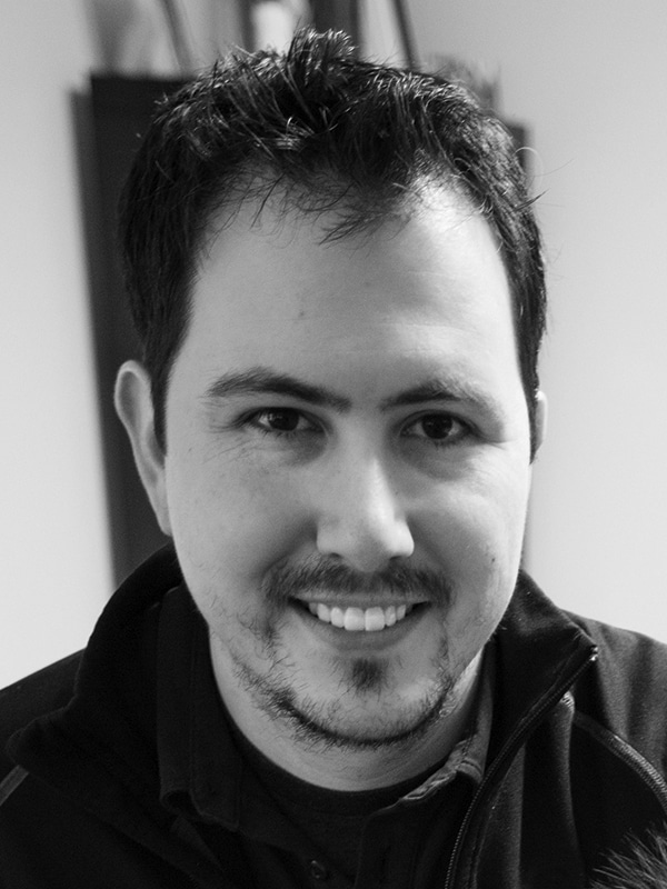 Close-up of a young man smiling, black and white photo emphasizing facial features and expression.