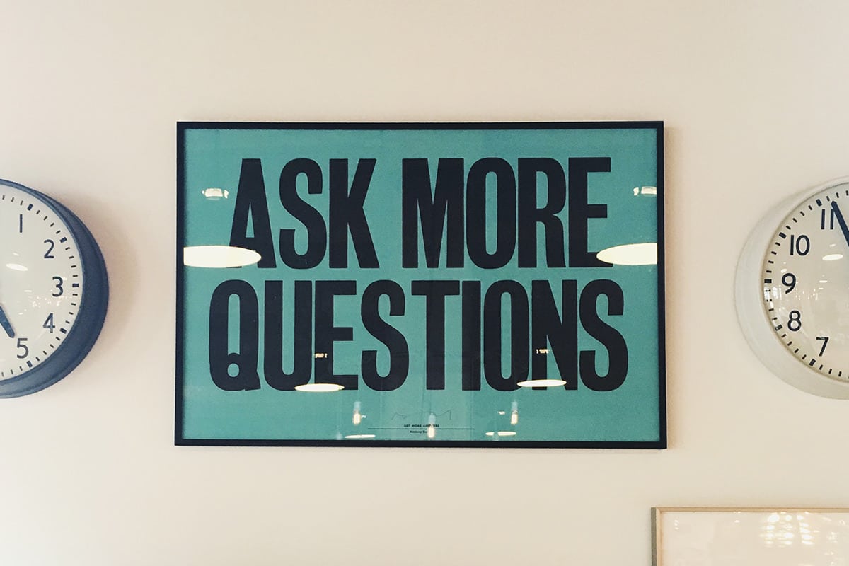 Bright blue sign with bold black text "Ask More Questions" for office or educational decor.