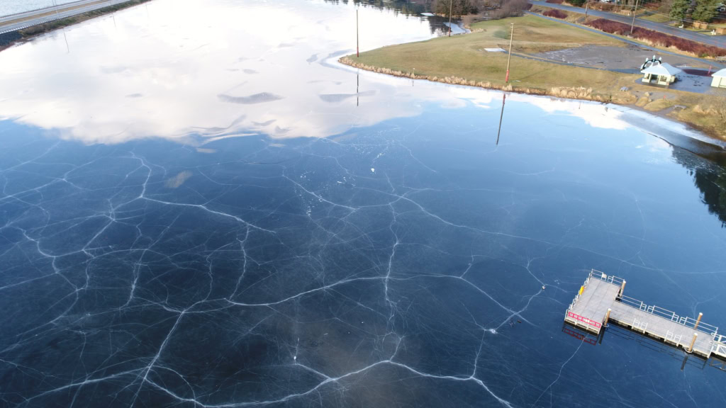 Lake ice reflecting the sky beside a dock