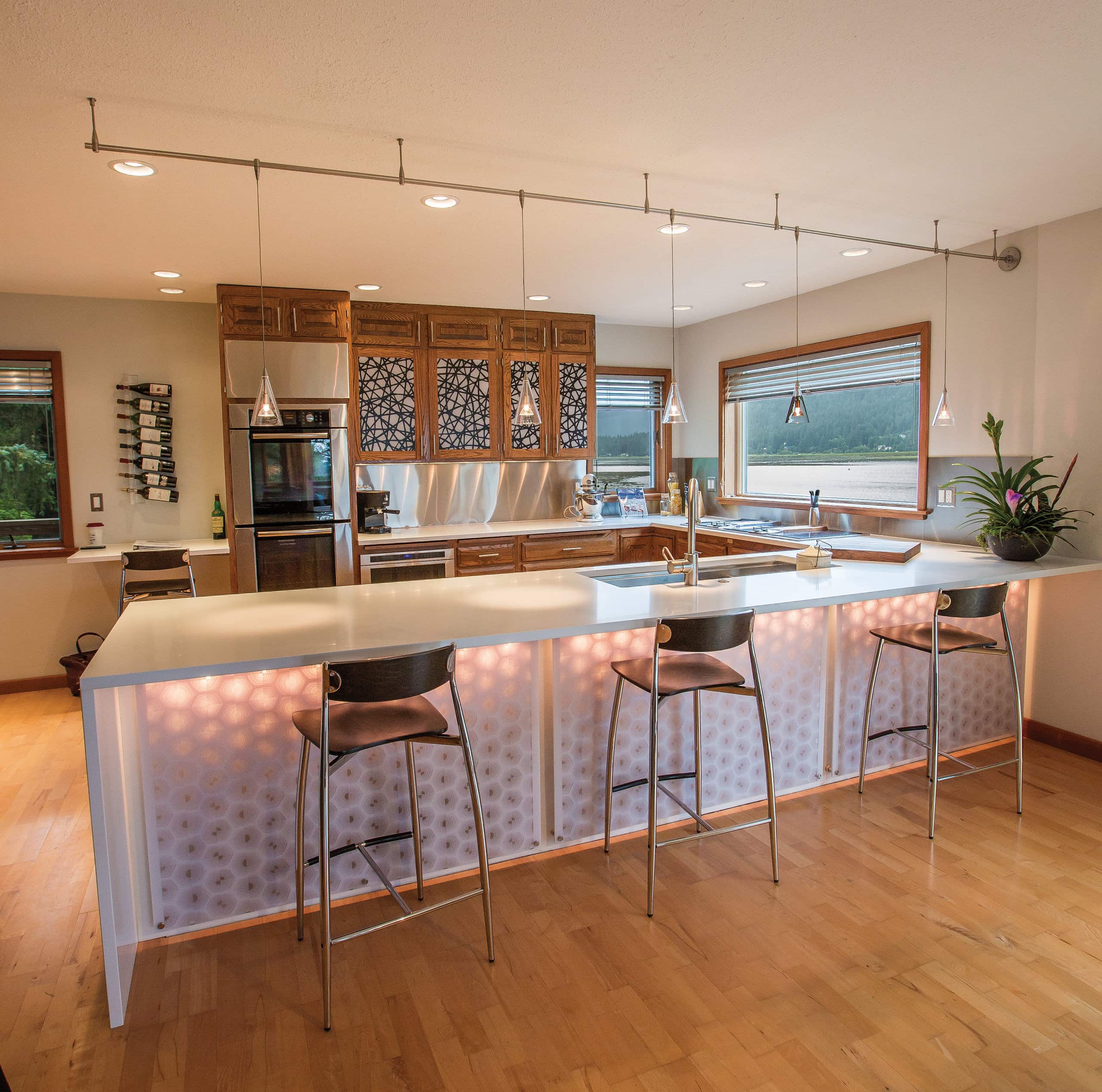 Bright kitchen with island, pendant lights, wooden cabinets, and lakeside windows.