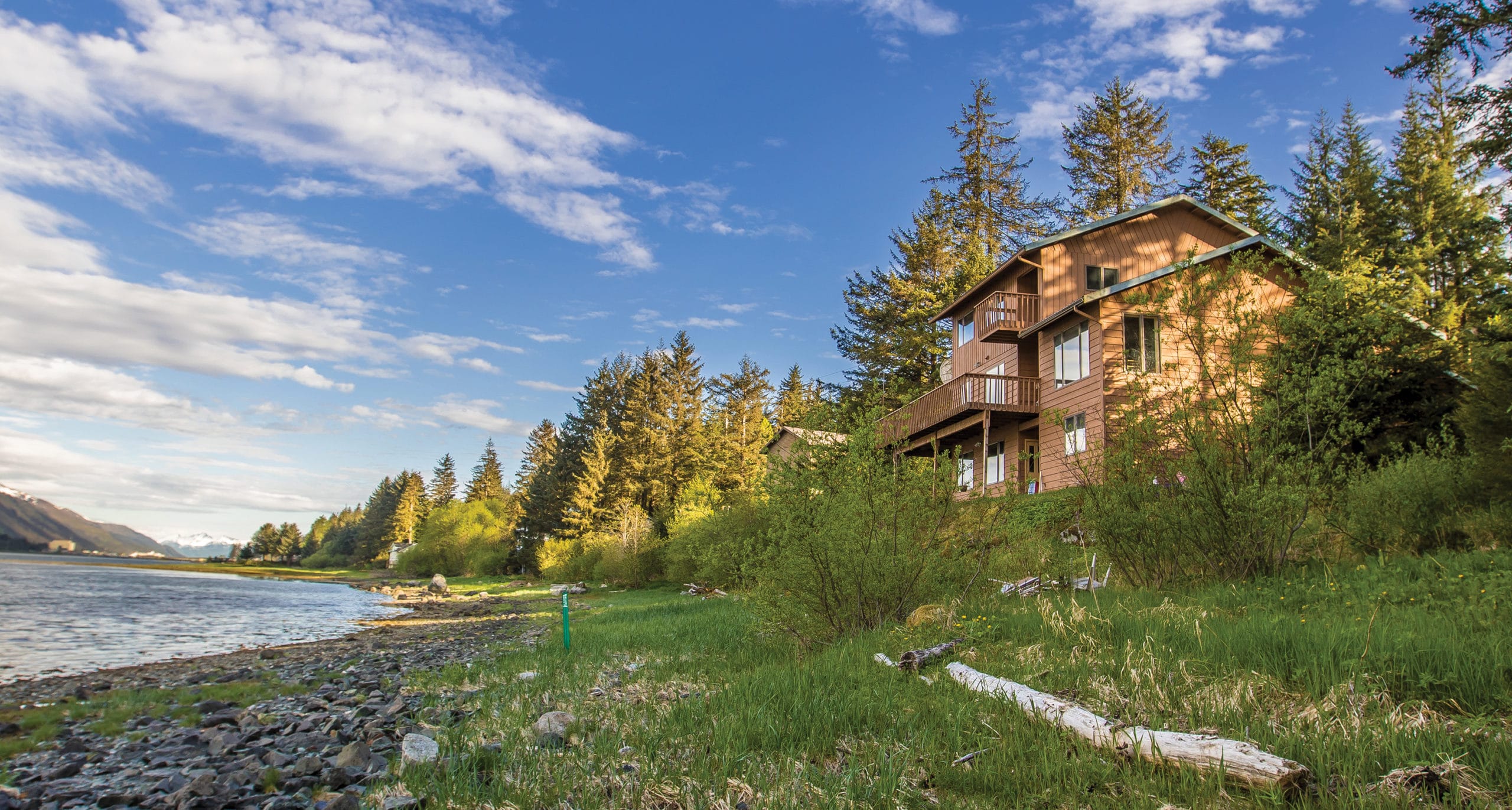 Cozy mountain cabin overlooking river surrounded by dense forest and vibrant landscape.