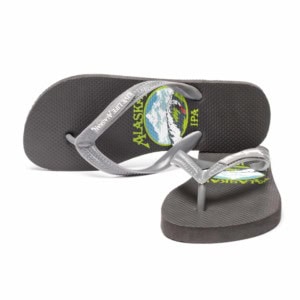 Pair of dark gray flip-flops with gray straps and the Alaskan IPA label art printed on the footbed.