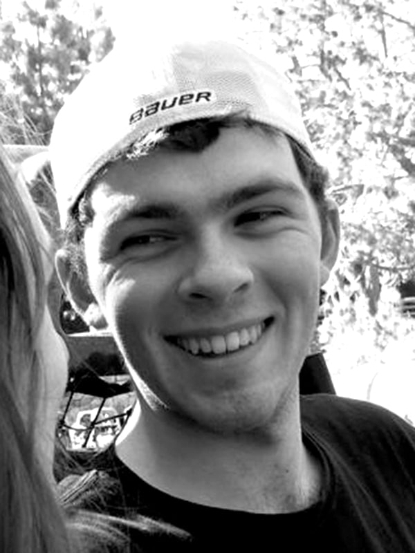 Young man smiling outdoors, wearing a baseball cap, representing fun and active lifestyle.