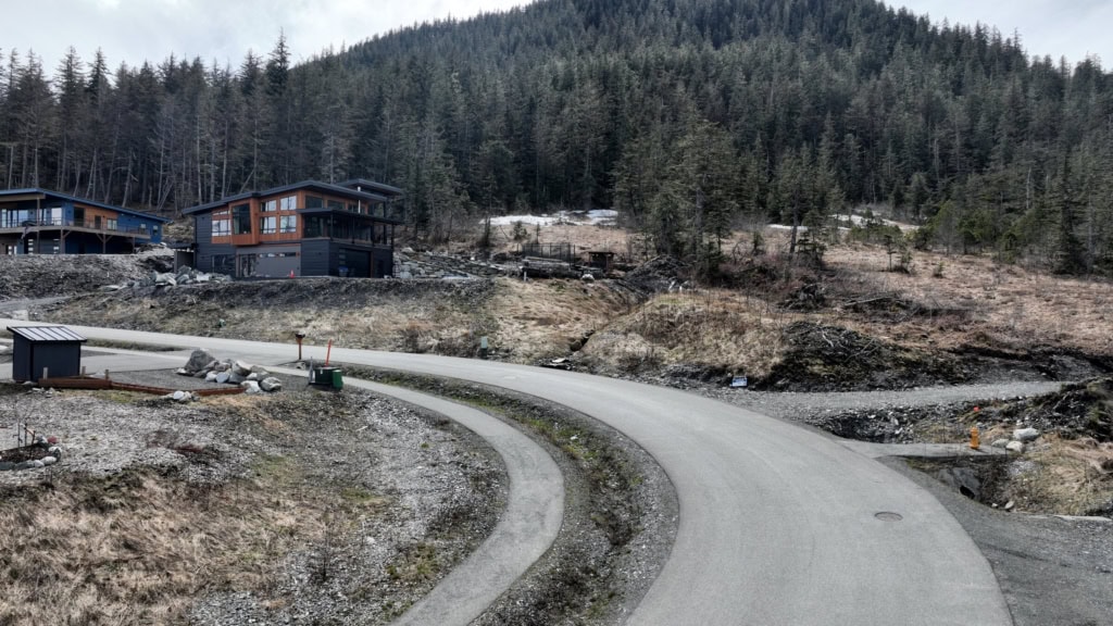 Newly graded road on a hillside with houses above