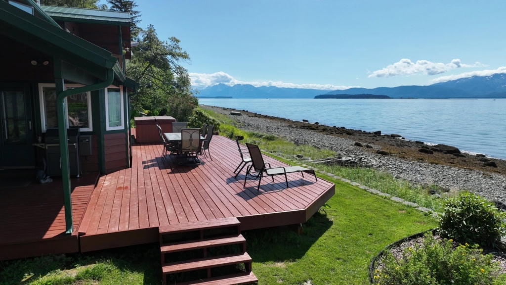 Red deck with stairs overlooking a beach and calm water