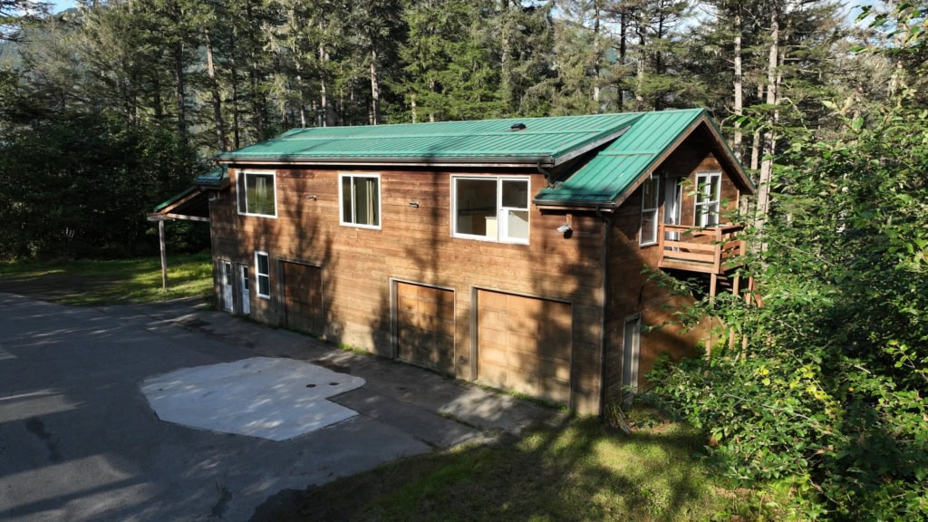 Cedar house with green metal roof in a wooded clearing