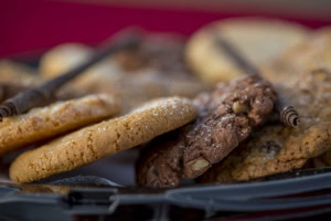 Close-up of sugar and chocolate nut cookies with rolled chocolate sticks on a tray, red background.