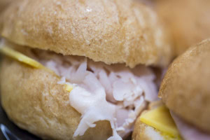 Extreme close-up of a slider with shaved turkey and a slice of cheese in a soft wheat roll.