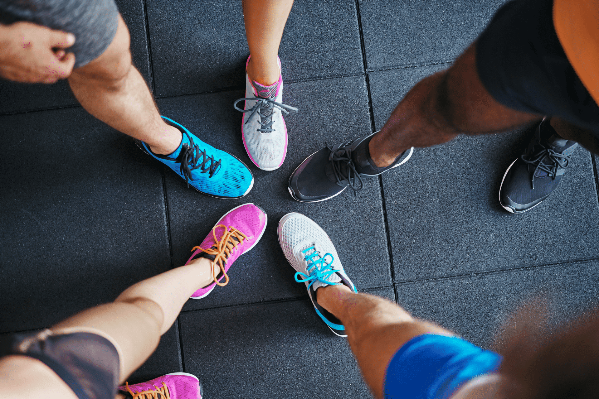 Vibrant running shoes in lively colors arranged in a circle on gym floor.