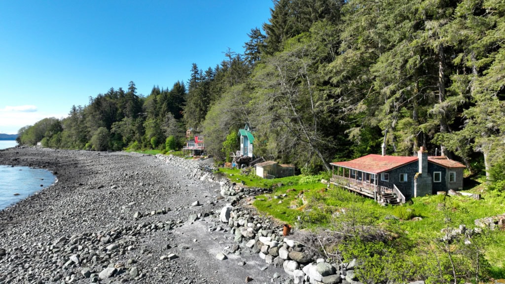 Red-roofed cabin above a rocky beach