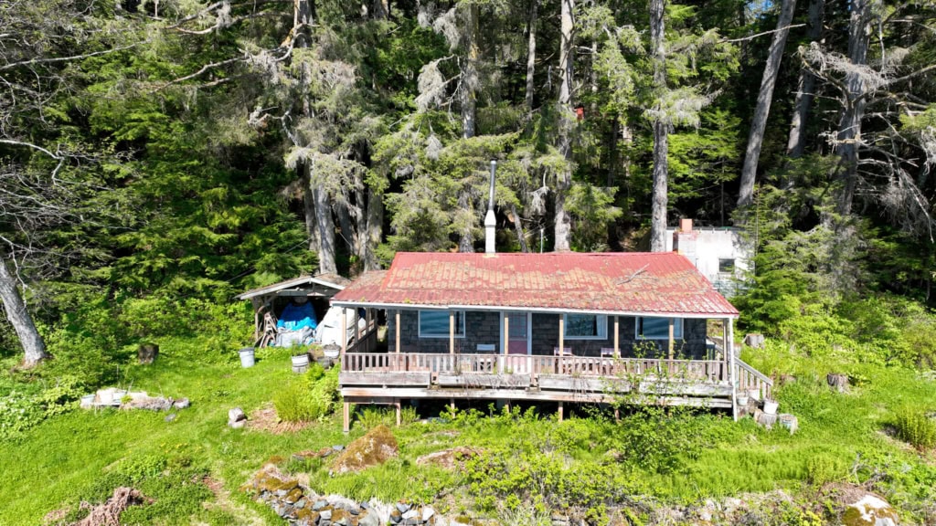 Red-roofed cabin with a covered porch among trees