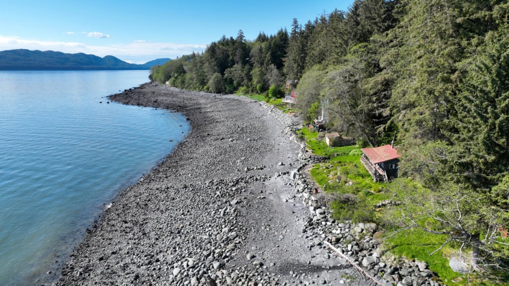 Curving rocky beach with a cabin among trees