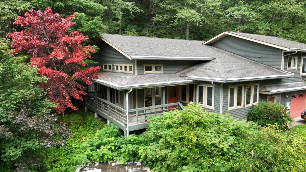 Elevated view of a gray house with a porch and gardens