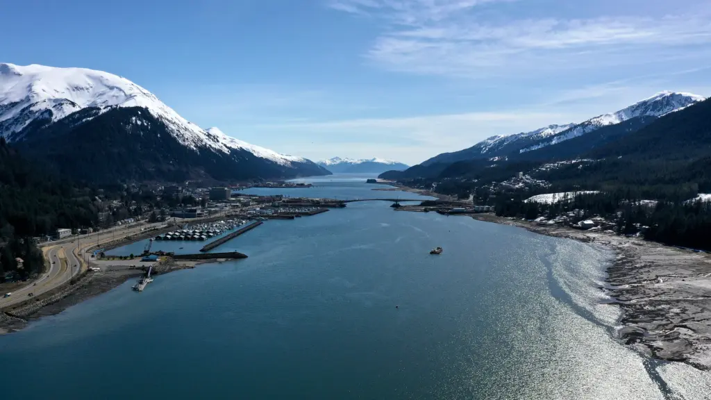Aerial view up Gastineau Channel past downtown Juneau harbors and the Juneau-Douglas bridge between snow-capped mountains