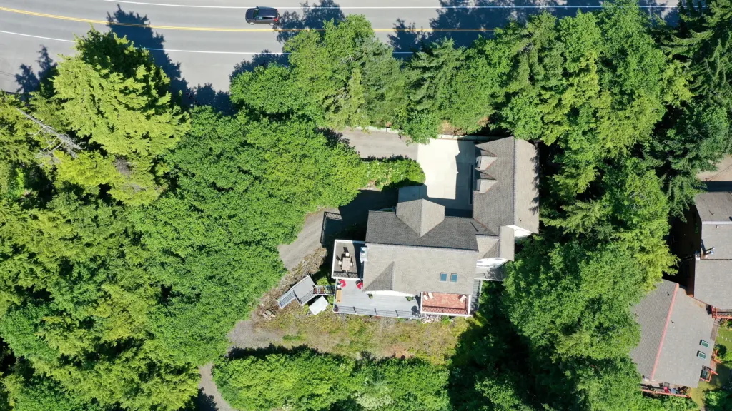 Top-down view of a home with patio and garden surrounded by lush green trees