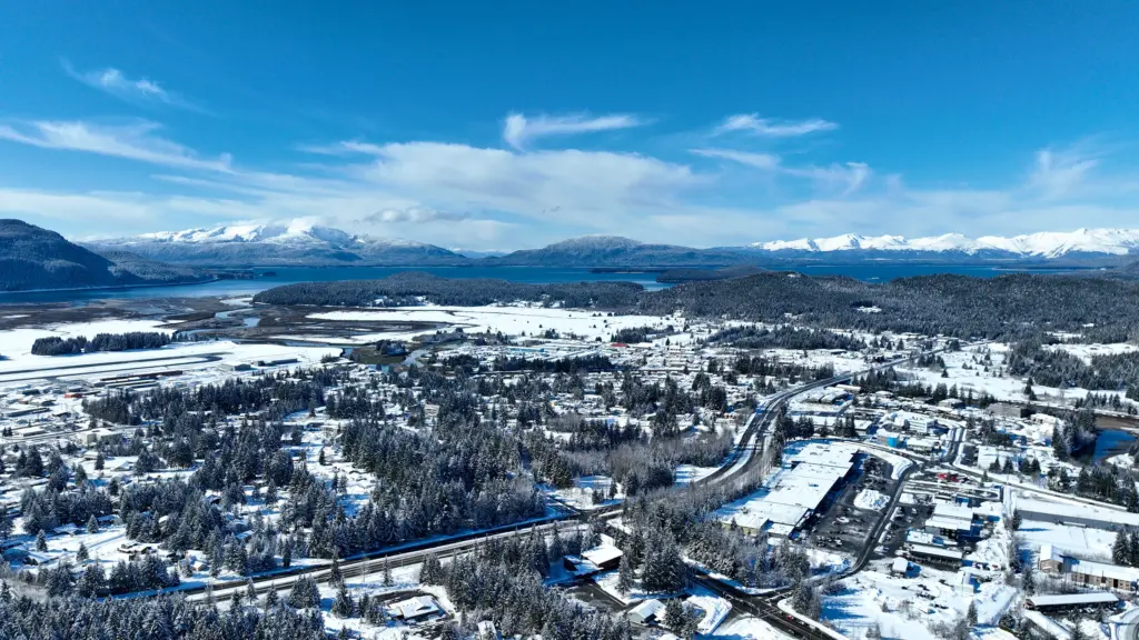 Snowy neighborhoods, the airport and wetlands spread below mountains on a clear day