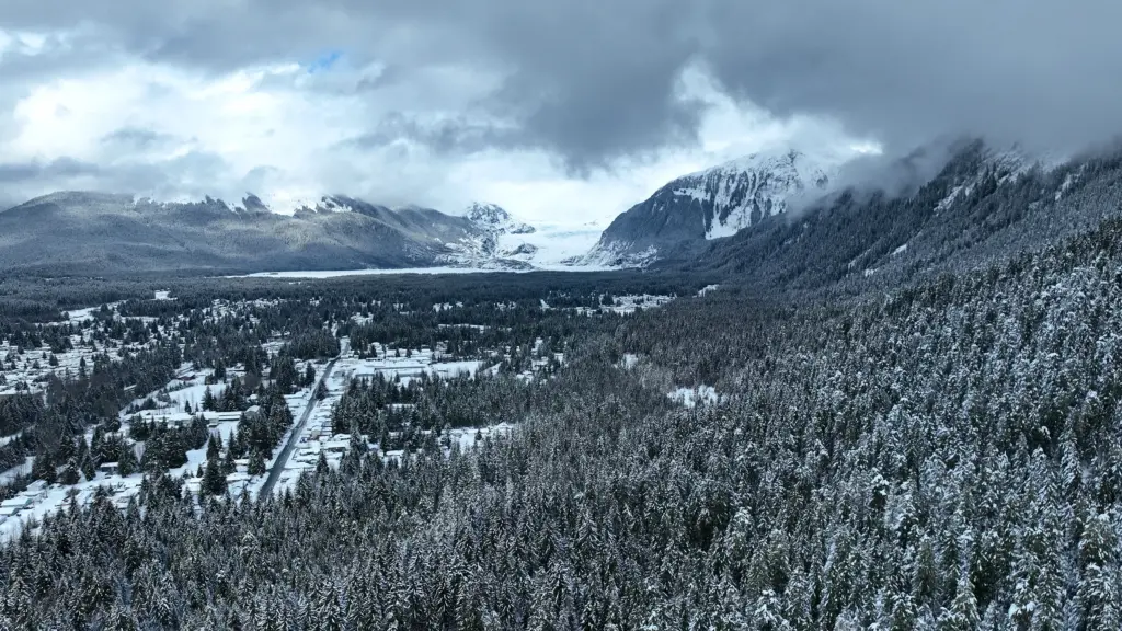 Clouds wrapping snowy mountains and a glacier above a snowy valley