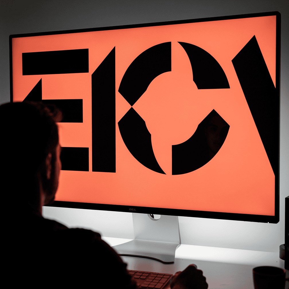 Monitor showing a bold website design with huge abstract letter shapes filling the screen